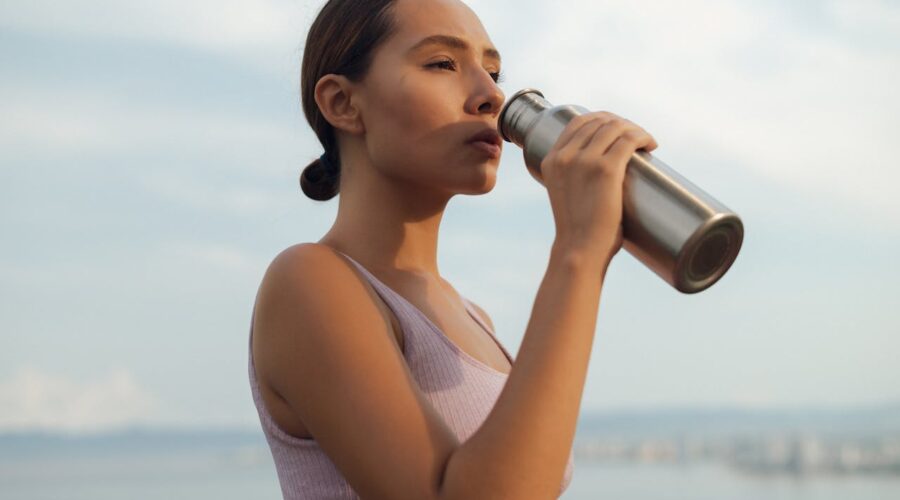 Mujer bebiendo agua al aire libre
